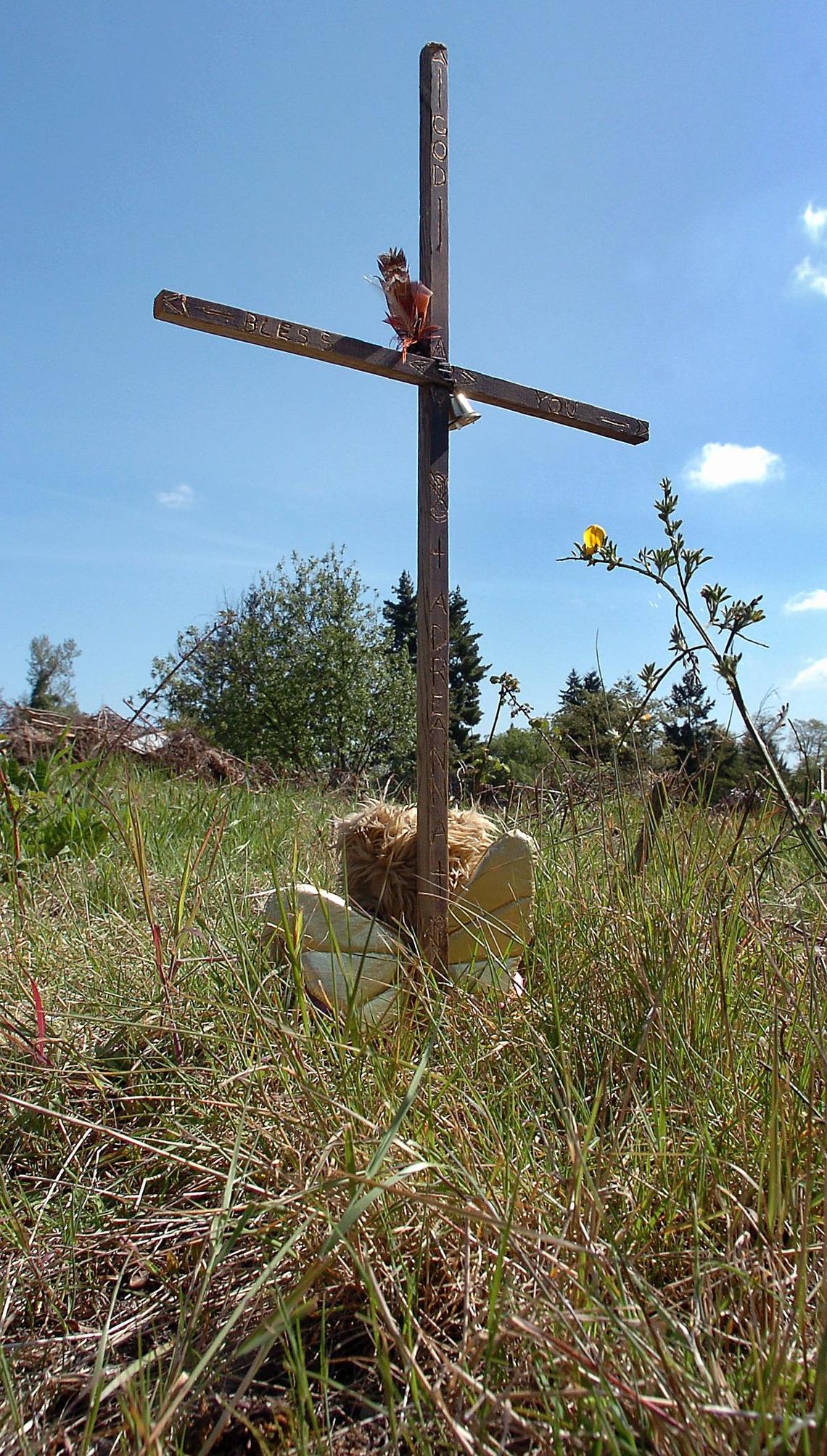 A 3-foot tall wooden cross, accompanied by a plush animal angel, is displayed on May 9, 2006, in the vacant Lakewood lot where the remains of 10-year-old Adre'anna Jackson were found. The cross is inscribed "God Bless You Adre'anna."