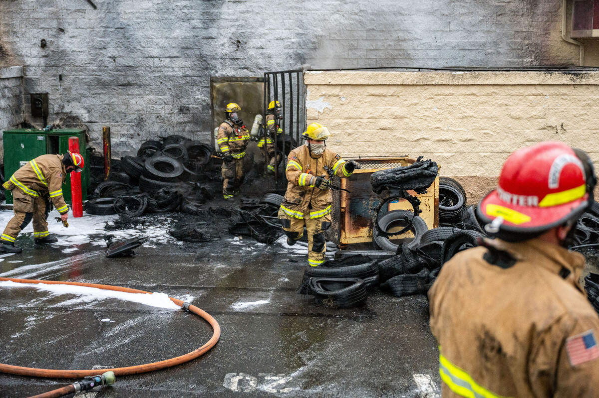 A firefighter from the Tacoma Fire Department tosses a discarded tire into a pile at a tire shop in the 1000 block of North Pearl Street in Tacoma, Wash., on Monday, Jan. 10, 2022. Earlier in the morning large pile of discarded tires caught fire along the side of the tire shop. No injuries were reported and the fire is under investigation.