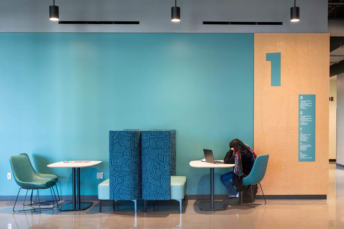 A student works from an open space on the first floor of the new Center for Innovative Learning and Engagement at Tacoma Community College on Wednesday, April 23, 2025. Each of the building’s three floors has been painted to recognize each level of Mount Rainier’s landscape, visible from the upper floors of the building – green for the forest level, teal for the timberline level and light blue for the alpine level.
