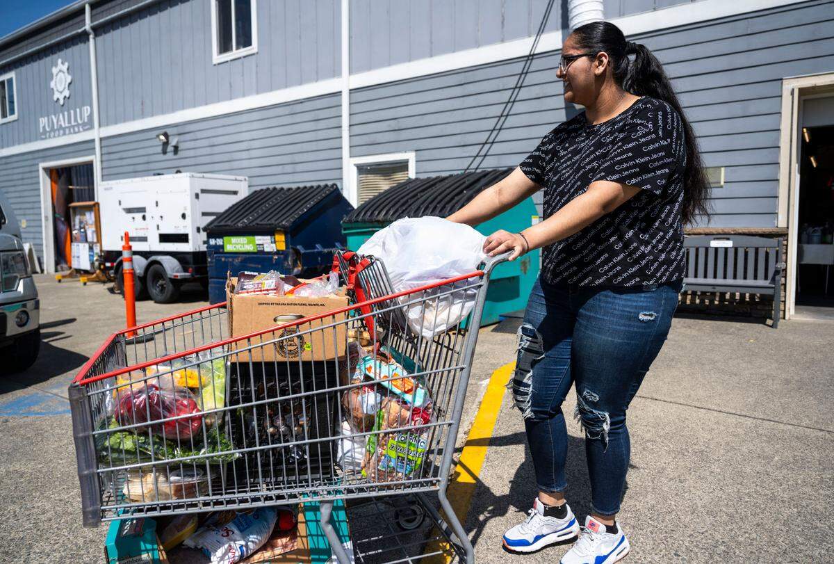 Puyallup High School senior Gurnoor Nagra delivers food in a shopping cart to families waiting in their cars outside of the Puyallup Food Bank in Puyallup, Wash. on April 27, 2023. Nagra has been volunteering at the food bank for about two years and has dedicated over 400 volunteer hours to helping her community.