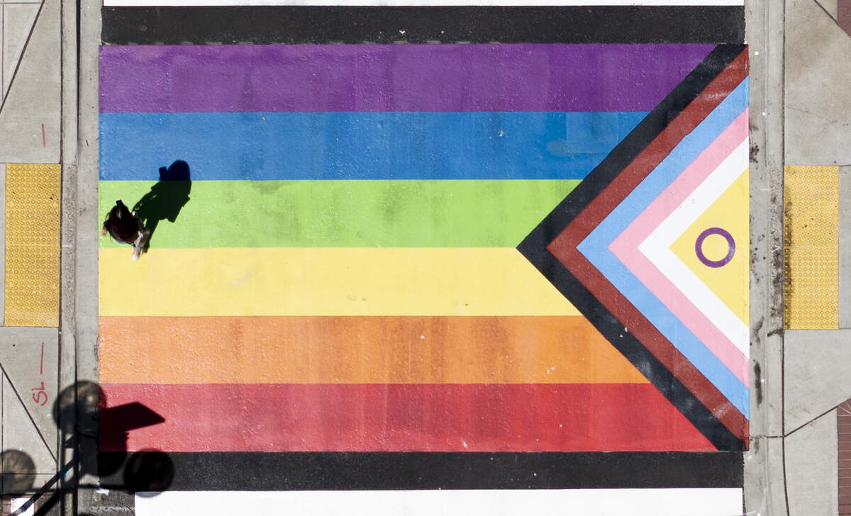 A person walks across the newly painted Pride Flag crosswalk mural in Tacoma, Wash.