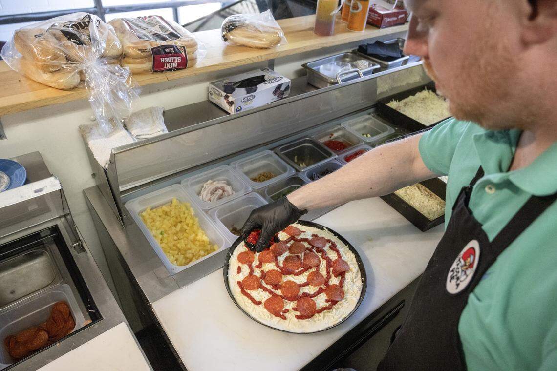 Lucas Drawdy, a manager at Tacoma Pie, adds toppings to a Tavern Style pizza on Friday, April 10, 2026, in Tacoma.