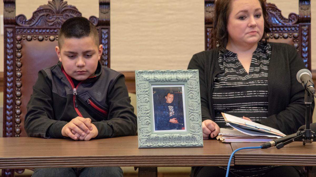 Julian (left) and Freedom Nitschke sit with a photo of Freedom’s father Timothy, who was murdered last year by a patient with a violent past living in the same adult living home.