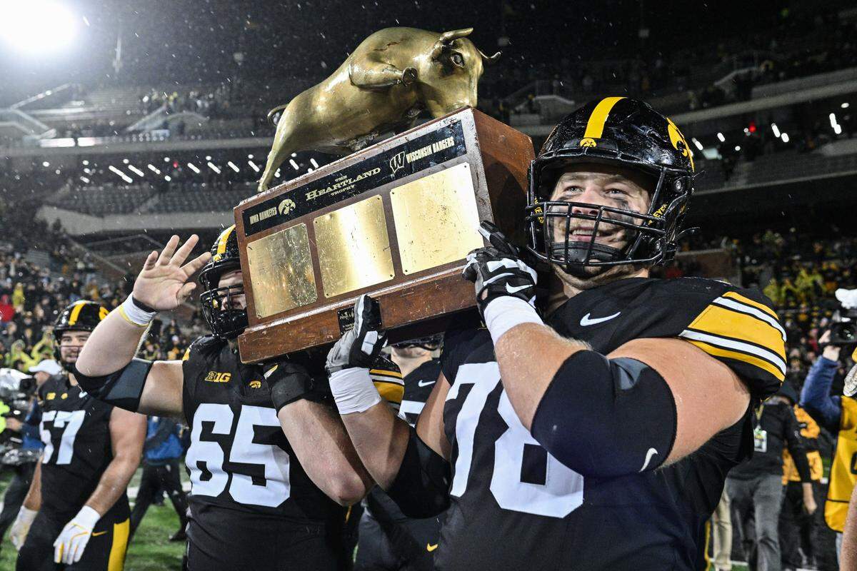 Nov 2, 2024; Iowa City, Iowa, USA; Iowa Hawkeyes offensive lineman Logan Jones (65) and offensive lineman Mason Richman (78) carry the Heartland trophy after the game against the Wisconsin Badgers at Kinnick Stadium. Mandatory Credit: Jeffrey Becker-Imagn Images