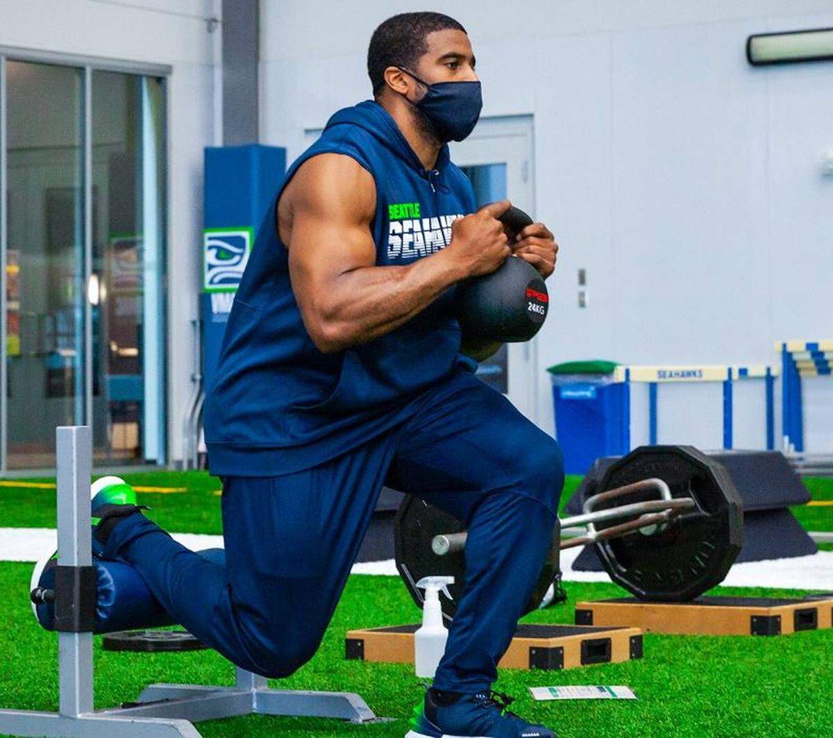 All-Pro linebacker Bobby Wagner lifts weights while wearing a mask and socially distanced on the Seahawks’ indoor practice field during training camp.