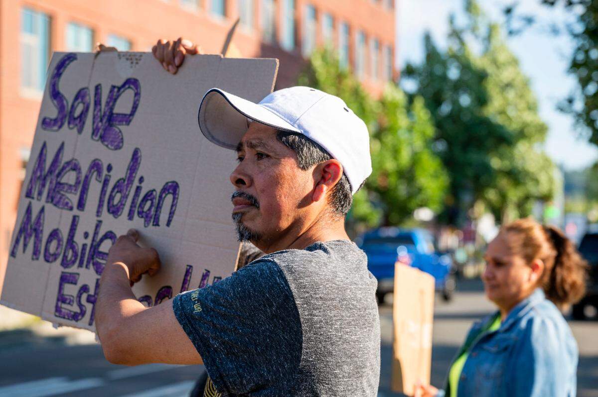 Martin Martinez, a resident at Meridian Mobile Estates, holds up a sign, while standing outside of Puyallup City Hall during a rally prior to a Puyallup City Council meeting on Tuesday, Aug. 23, 2022.
