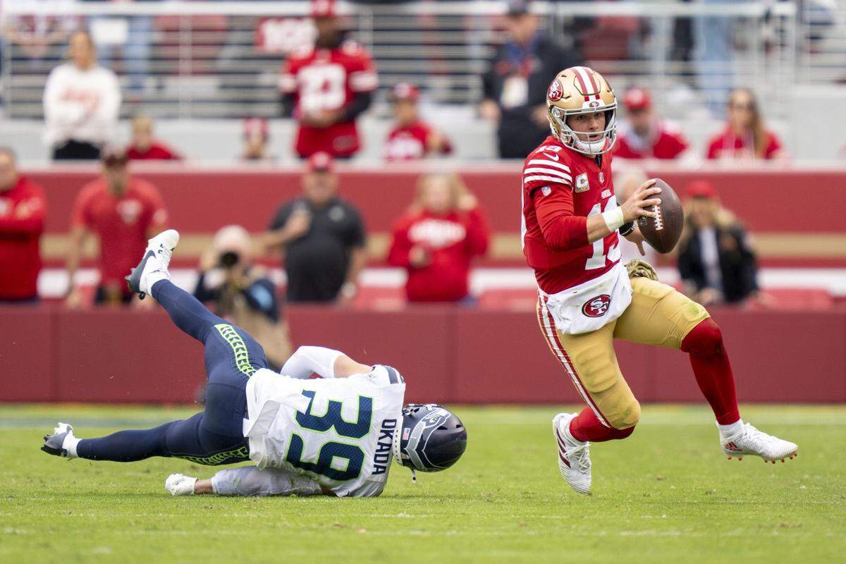 November 17, 2024; Santa Clara, California, USA; San Francisco 49ers quarterback Brock Purdy (13) runs past Seattle Seahawks safety Ty Okada (39) during the second quarter at Levi's Stadium. Mandatory Credit: Kyle Terada-Imagn Images
