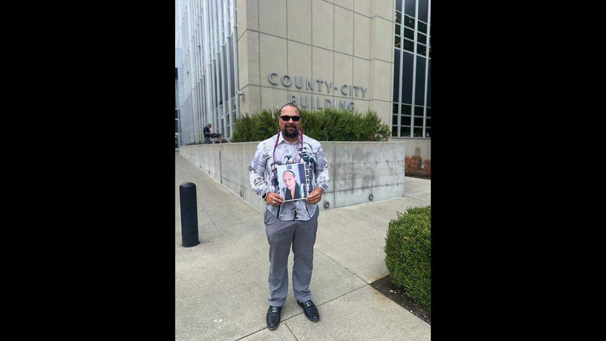 Willard Palmer, 40, holds a photograph of his sister, Angelina Palmer, outside the County-City Building in Tacoma on Aug. 4, 2025. Angelina was fatally shot outside a 7-Eleven in Spanaway in a shooting that stemmed from an argument she had no part in.