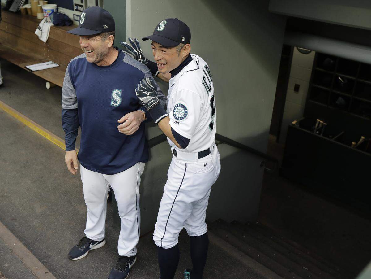 Seattle Mariners' Ichiro Suzuki, right, laughs with hitting coach Edgar Martinez as Suzuki prepares to exit the dugout at the start of a baseball game between the Mariners and the Oakland Athletics, Thursday, May 3, 2018, in Seattle. Suzuki was released Thursday by the Mariners and is shifting into a front office role with the team, so he cannot be in the dugout while the game is being played. (AP Photo/Ted S. Warren)