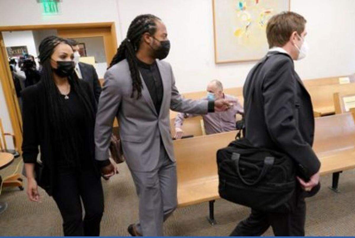 Former Seahawks Super Bowl-champion cornerback Richard Sherman enters King County District Court in Seattle Friday holding the hand of his wife Ashley, left, and trailing defense attorney Cooper Offenbecher, right. Sherman pleaded not guilty to five charges stemming from incidents in suburban Redmond early Wednesday.