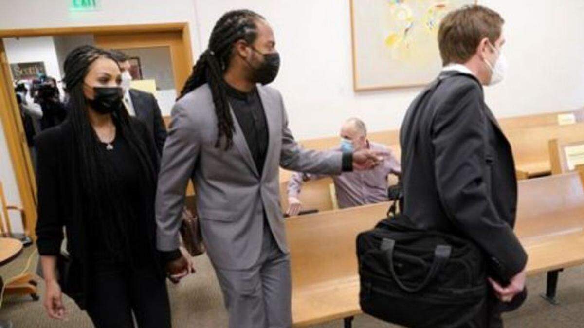 Former Seahawks Super Bowl-champion cornerback Richard Sherman enters King County District Court in Seattle Friday holding the hand of his wife Ashley, left, and trailing defense attorney Cooper Offenbecher, right. Sherman pleaded not guilty to five charges stemming from incidents in suburban Redmond early Wednesday.