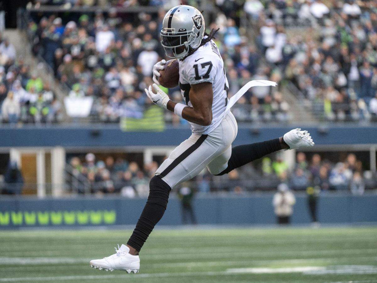 Las Vegas Raiders wide receiver Davante Adams (17) catches a pass from quarterback Derek Carr (4) as Seattle Seahawks cornerback Mike Jackson (30) defends during the second quarter of an NFL game on Sunday, Nov. 27, 2022, at Lumen Field in Seattle.
