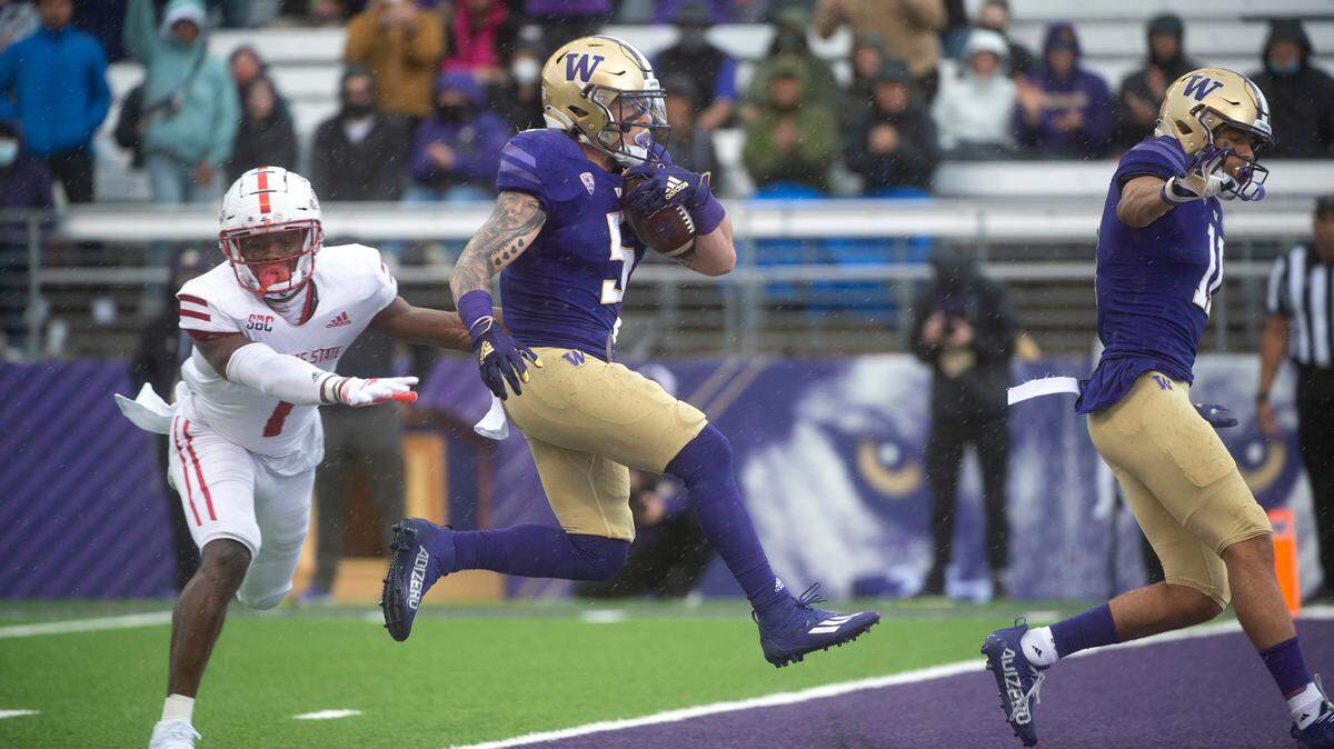 Huskies tailback Sean McGrew pops into the end zone in front of Arkansas State safety Anthony Switzer for a 13-yard touchdown run during Saturday’s NCAA football game at Husky Stadium in Seattle, Washington, on Sept. 18, 2021.