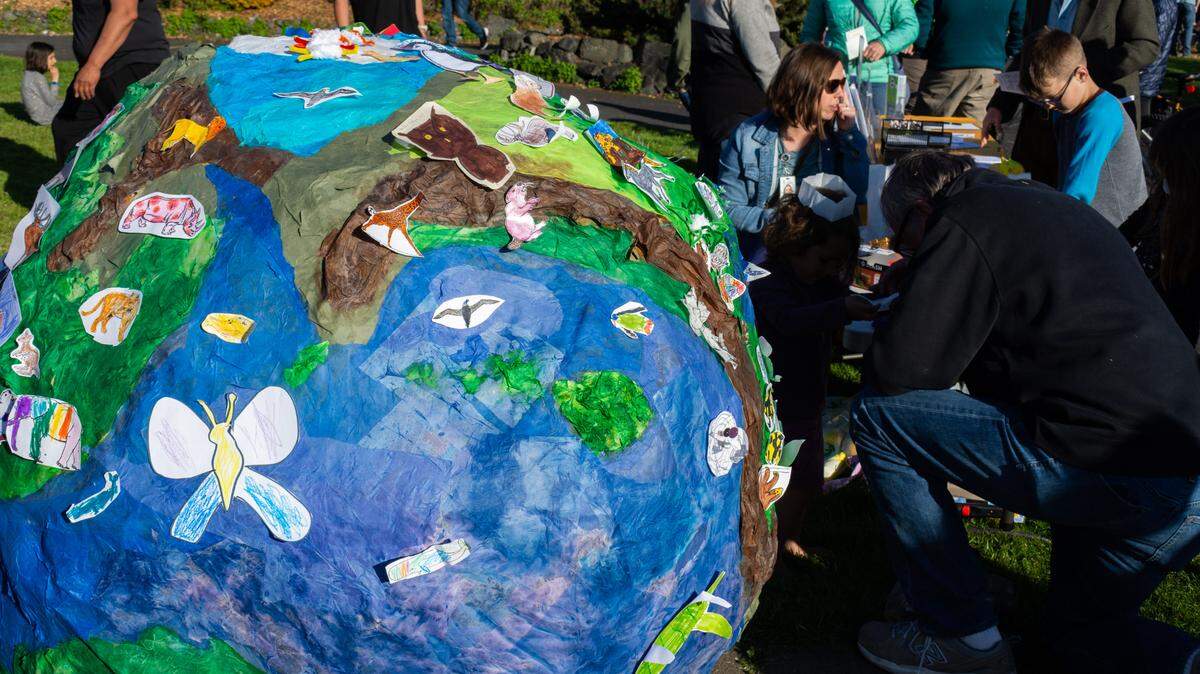 Children color and tape handmade paper animals on the Whatcom Museum’s paper mache model earth at the Children of the Setting Sun Production’s Mother Earth Day celebration Friday, April 22, 2022, at Maritime Heritage Park in Bellingham, Wash.