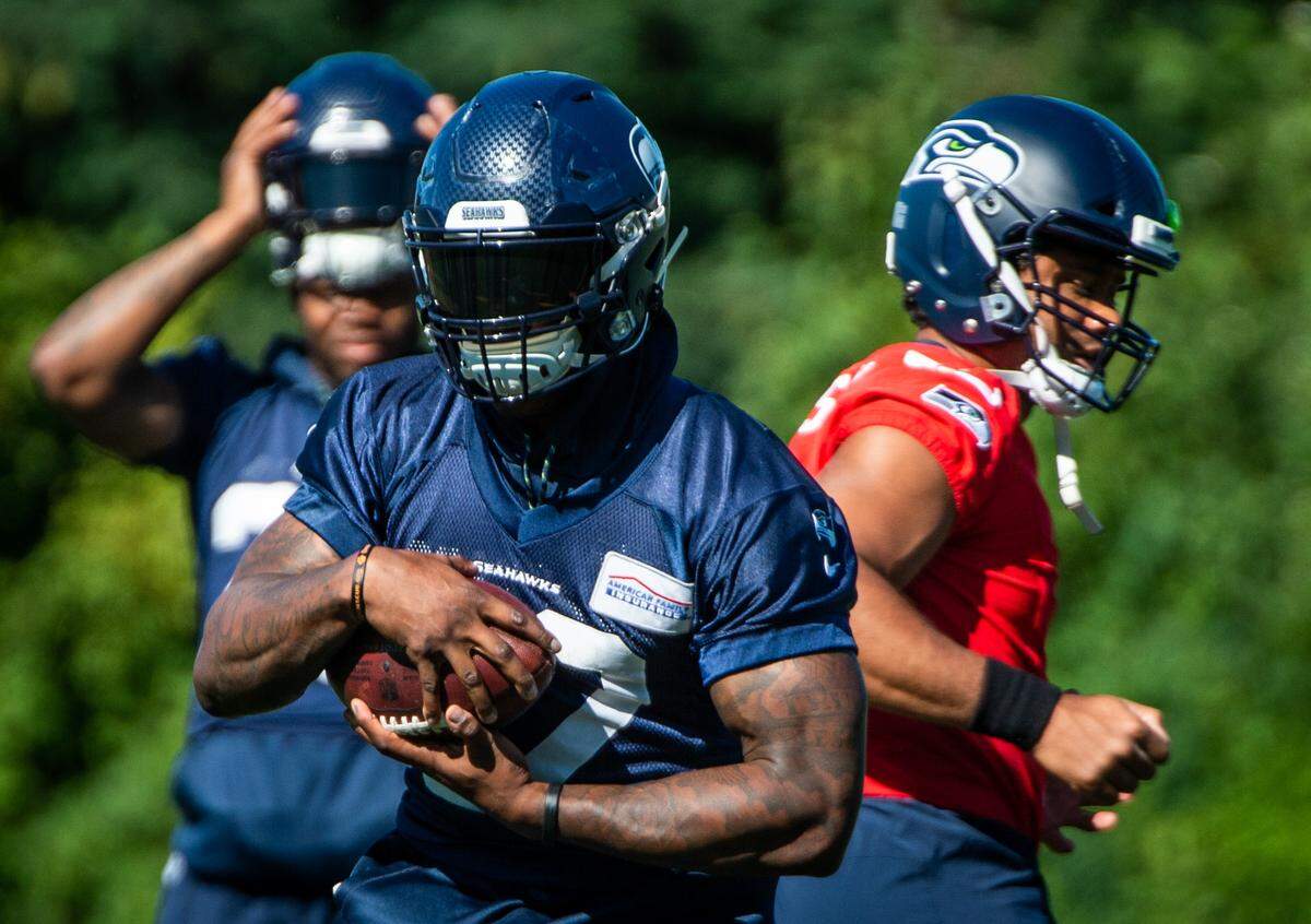 Chris Carson gets the ball from Russell Wilson during the Seattle Seahawks training camp at the Virginia Mason Athletic Center in Renton, Wash., on Thursday, July 25, 2019.