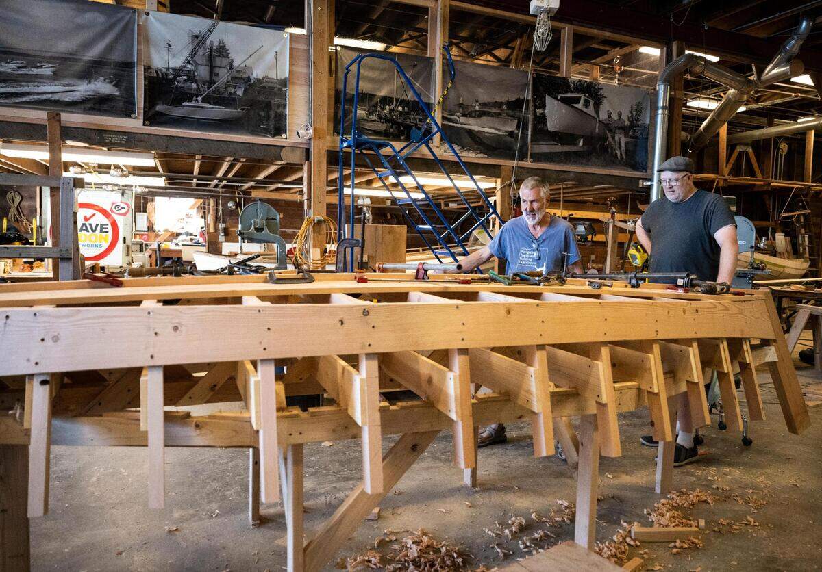 Jonathan Cunningham, right, and Anthony “Mike” Vlahovich, left, work on a Croatian fishing boat that is being built as part of “The Batana Project” at the Gig Harbor Boat Shop in Gig Harbor, Wash. on Wednesday, July 20, 2022. Once the boat is complete, the boat shop will host an event to reveal it Sept. 3.