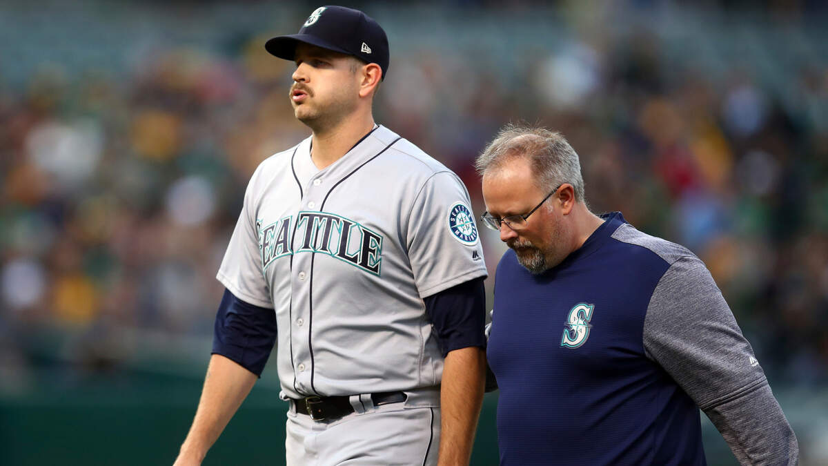 Seattle Mariners pitcher James Paxton, second from left, is escorted off the field after being hit by a ball in the first inning of a baseball game against the Oakland Athletics Tuesday, Aug. 14, 2018, in Oakland, Calif. (AP Photo/Ben Margot)