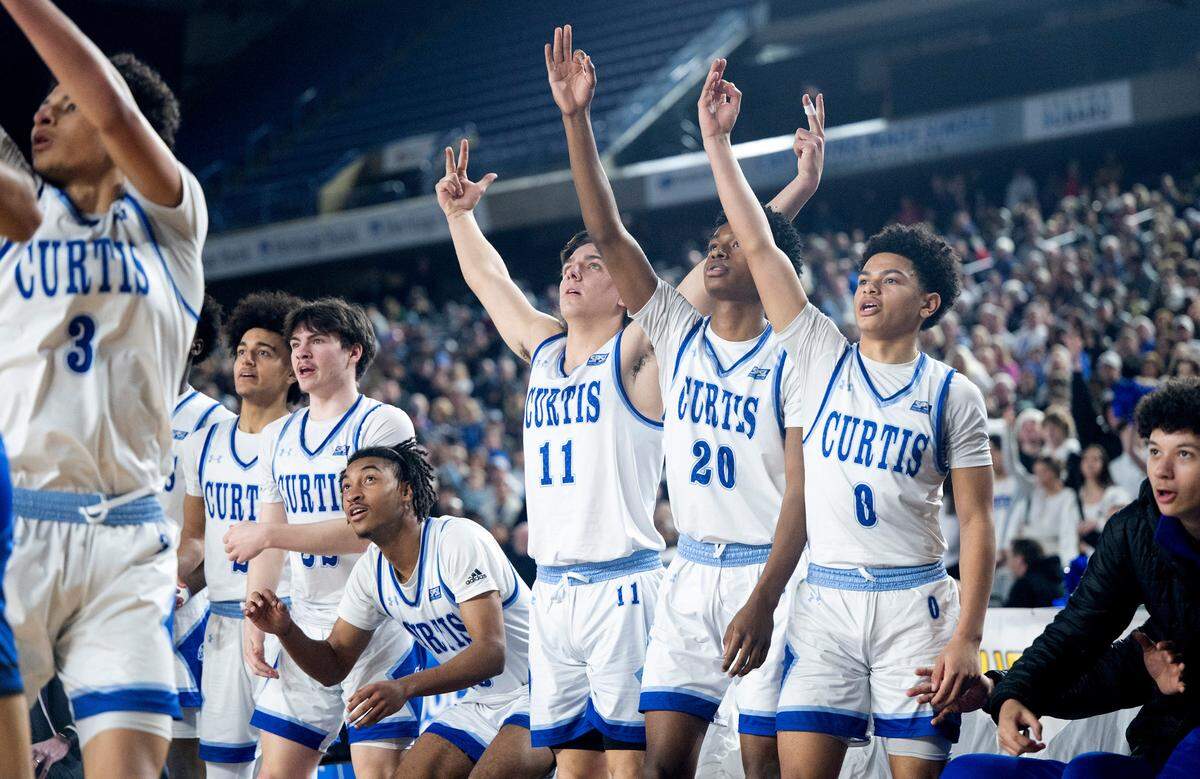 Curtis players watch as Devin Whitten launches a three-point attempt during the Vikings’ state semifinal game against the Federal Way Eagles at the WIAA state basketball tournament in the Tacoma Dome in Tacoma, Washington, on Friday, March 3, 2023. Curtis won the game, 56-43.