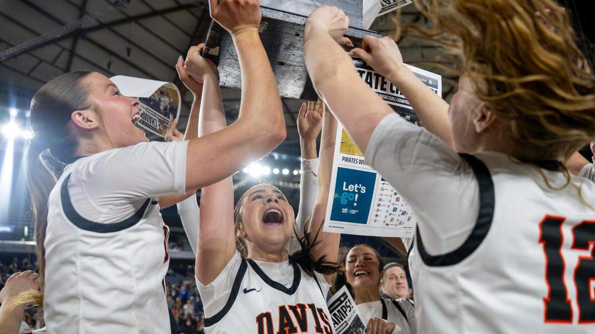 Davis’s Cheyenne Hull (left), Averie Brandt (center) and Ella Craig (right) hoist the Class 4A State Championship trophy after beating Sumner, 61-45, at the Tacoma Dome on Saturday, March 8, 2025, in Tacoma, Wash.