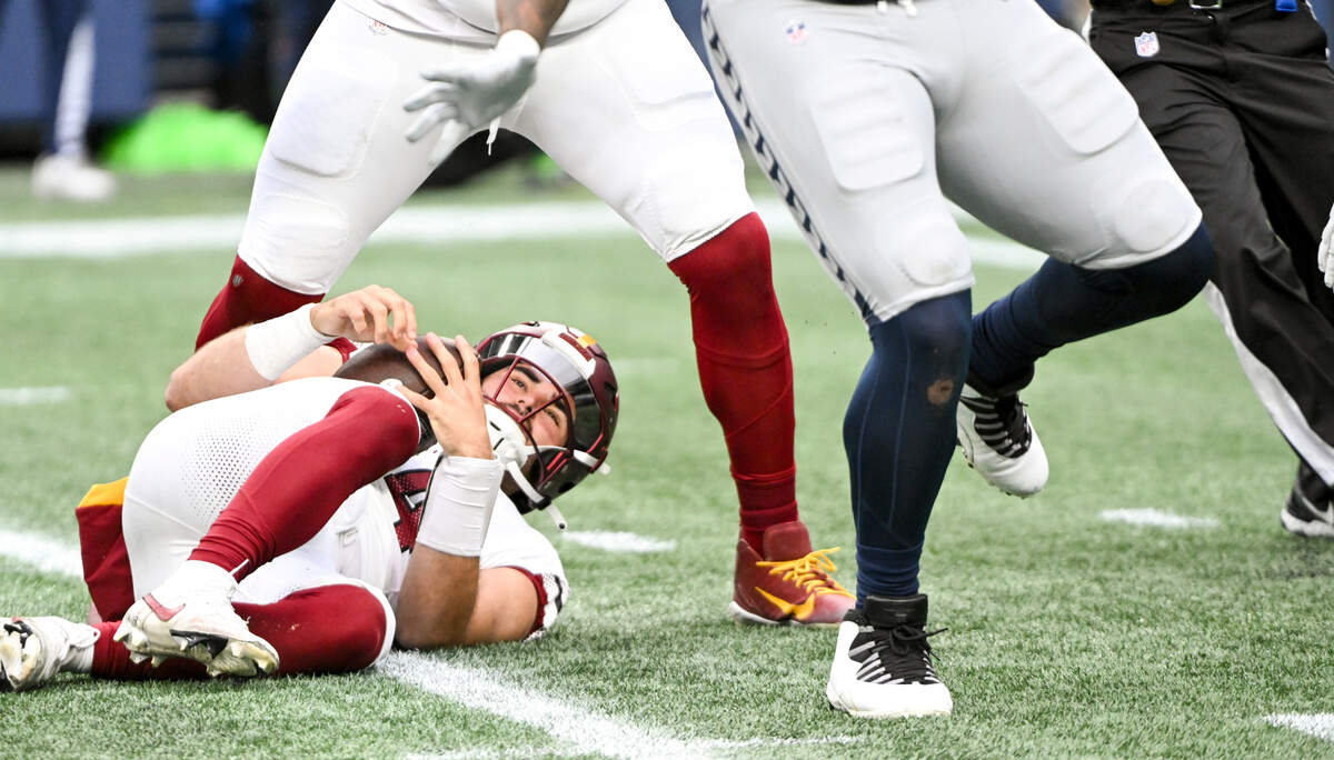 Washington Commanders quarterback Sam Howell (14) lays on the ground after being sacked by Seattle Seahawks defensive end Leonard Williams (99) during the second quarter of the game at Lumen Field, on Sunday, Nov. 12, 2023, in Seattle, Wash.