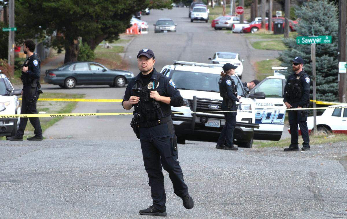Tacoma police keep watch at the scene of a shooting outside The Little Store on Ainsworth Avenue and 35th Street in Tacoma, Washington, on Tuesday, Oct. 3, 2023.