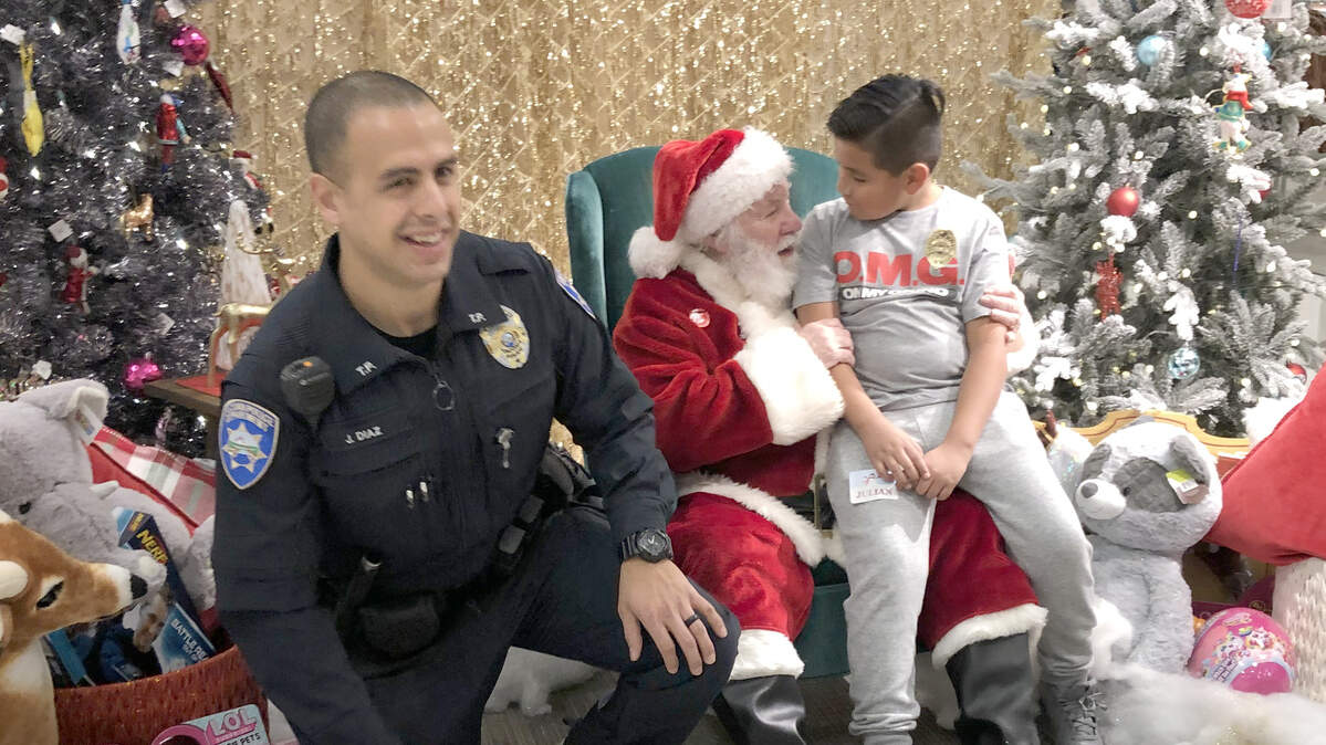 Tacoma police officer Juan Diaz and his shopping buddy Julian Clark, 9, pose with Santa at the Tacoma Target store Saturday during “Shop with a Cop.”