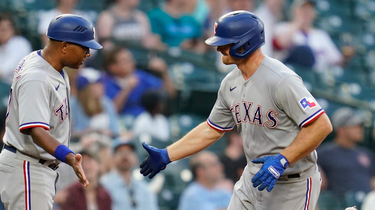 Texas Rangers’ John Hicks, right, is congratulated by third base coach Tony Beasley on Hicks’ solo home run in the fourth inning of a baseball game Saturday, July 3, 2021, in Seattle. (AP Photo/Elaine Thompson)