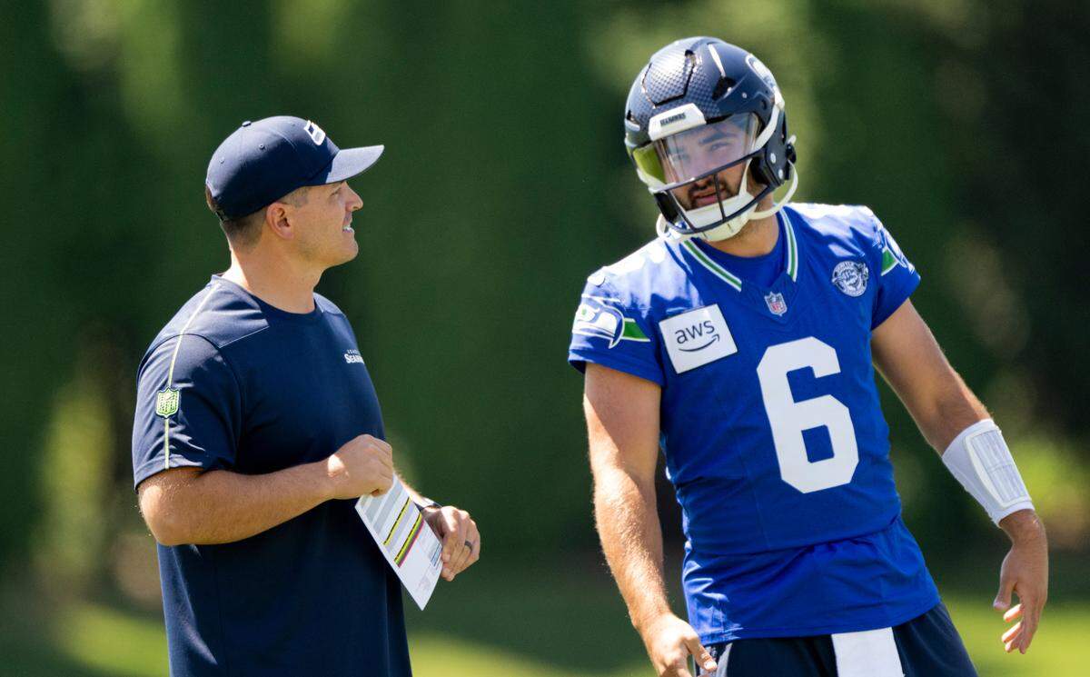 Head coach Mike MacDonald and backup quarterback Sam Howell (6) talk and during the first day of Seattle Seahawks training camp at the Virginia Mason Athletic Center, on Wednesday, July 24, 2024, in Renton.