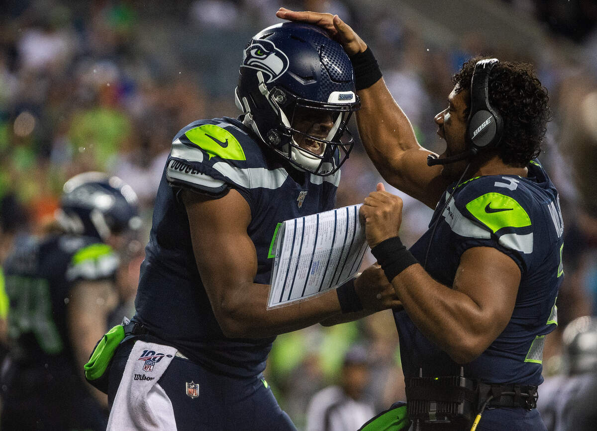 Seattle Seahawks quarterback Russell Wilson (3) celebrates with Seattle Seahawks quarterback Geno Smith (7) after Smith’s touchdown pass during the second quarter. The Seattle Seahawks played the Oakland Raiders in a National Football League game at CenturyLink Field in Seattle, Wash., on Thursday, Aug. 29, 2019.