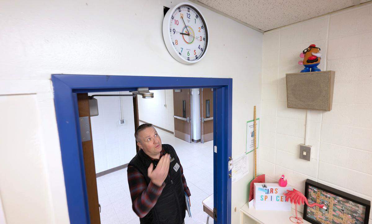 Capital projects director Brady Martin shows one of the makeshift clocks installed in classrooms at Spinning Elementary School in Puyallup, Washington, on Thursday, Jan. 30, 2025. The aging school’s clock system no longer works properly, often moving class bells off by a couple of minutes.