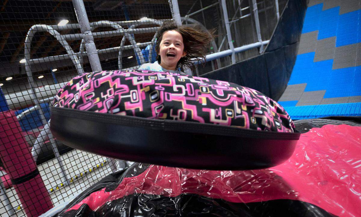 Olivia Mandez, 5, squeals with delight as she is launched into air on the Tube-Topia river rafting slide at Catapult Adventure Park in Puyallup, Washington, on Friday, Dec. 24, 2021.