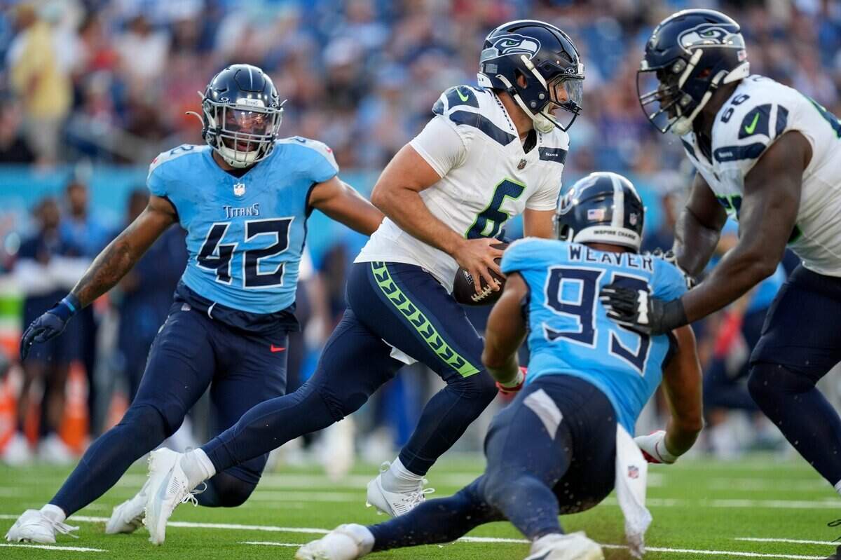 Seattle Seahawks quarterback Sam Howell (6) bolts between Tennessee Titans linebacker Caleb Murphy (42) and linebacker Rashad Weaver (99) during the first quarter at Nissan Stadium in Nashville, Tenn., Saturday, Aug. 17, 2024.
