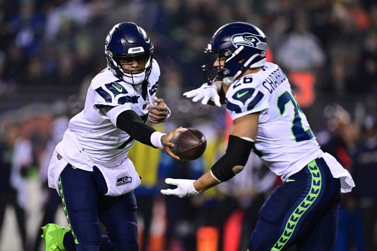 Dec 26, 2024; Chicago, Illinois, USA; Seattle Seahawks quarterback Geno Smith (7) hands the ball to running back Zach Charbonnet (26) against the Chicago Bears during the first quarter at Soldier Field. Mandatory Credit: Daniel Bartel-Imagn Images