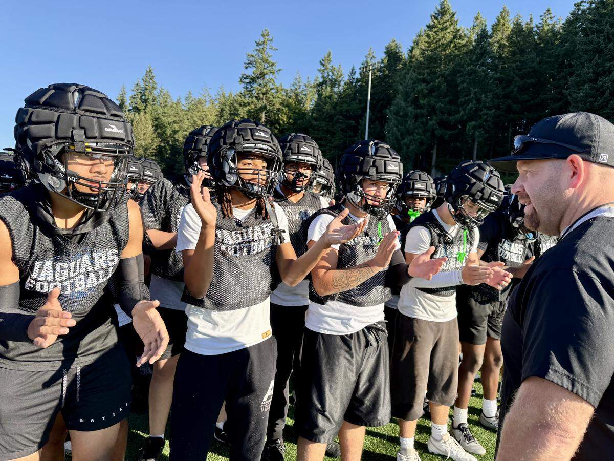 Emerald Ridge High School football players huddle in front of second-year coach Torey Donovan during practice at the high school in August of 2025.