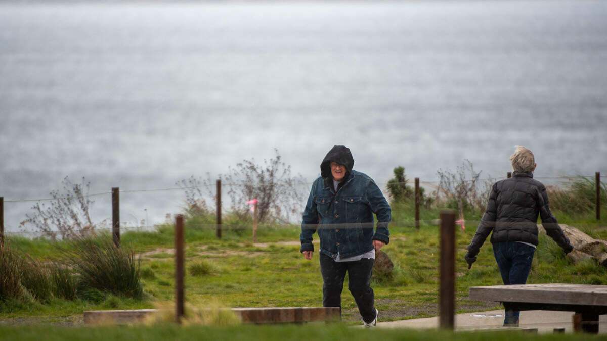 In this April 4, 2022 file photo, High winds make walking along Dune Peninsula difficult for these pedestrians in Tacoma, Wash.