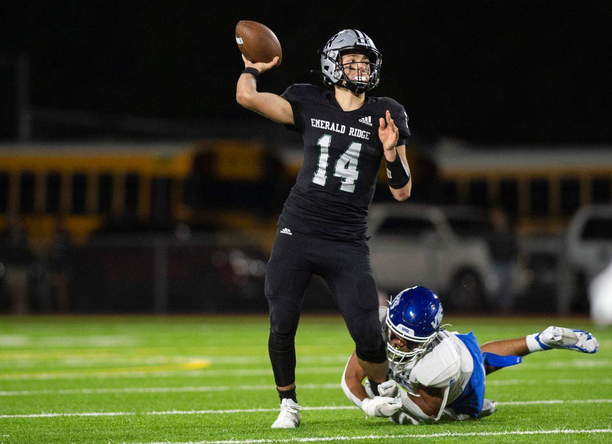 Emerald Ridge quarterback Jake Schakel (14) passes the ball while Curtis linebacker Felix Marfay-Diaz (6) holds on to his leg during the fourth quarter of a game at Sparks Stadium in Puyallup, Wash. on Sept. 22, 2022. Emerald Ridge defeated Curtis 42-13.