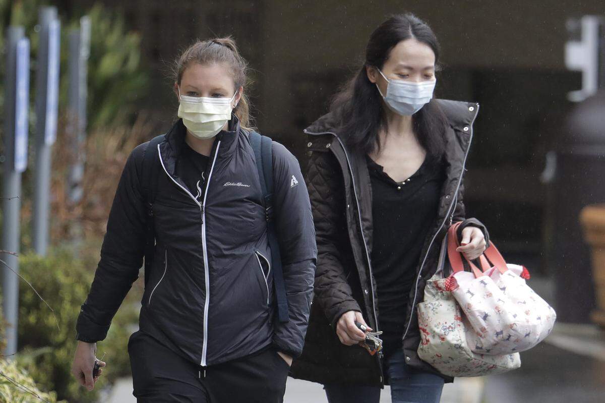 Two women wearing masks walk away from the Life Care Center in Kirkland, Wash., near Seattle, Monday, March 2, 2020. Washington has seen 18 confirmed cases, six of which have died, state health officer Dr. Kathy Lofy said during a news conference in Seattle on Monday. (AP Photo/Ted S. Warren)