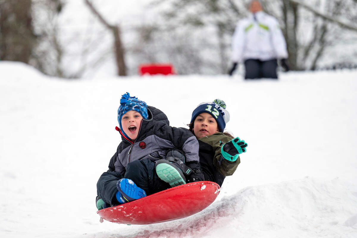 Blake Kirby, 5, and his sister, Stella, 7, do their best to hold on as they fly off the edge of a jump at Alling Park while their mom, Bianca, watches on Thursday, Dec. 30, 2021, in Tacoma, Wash.