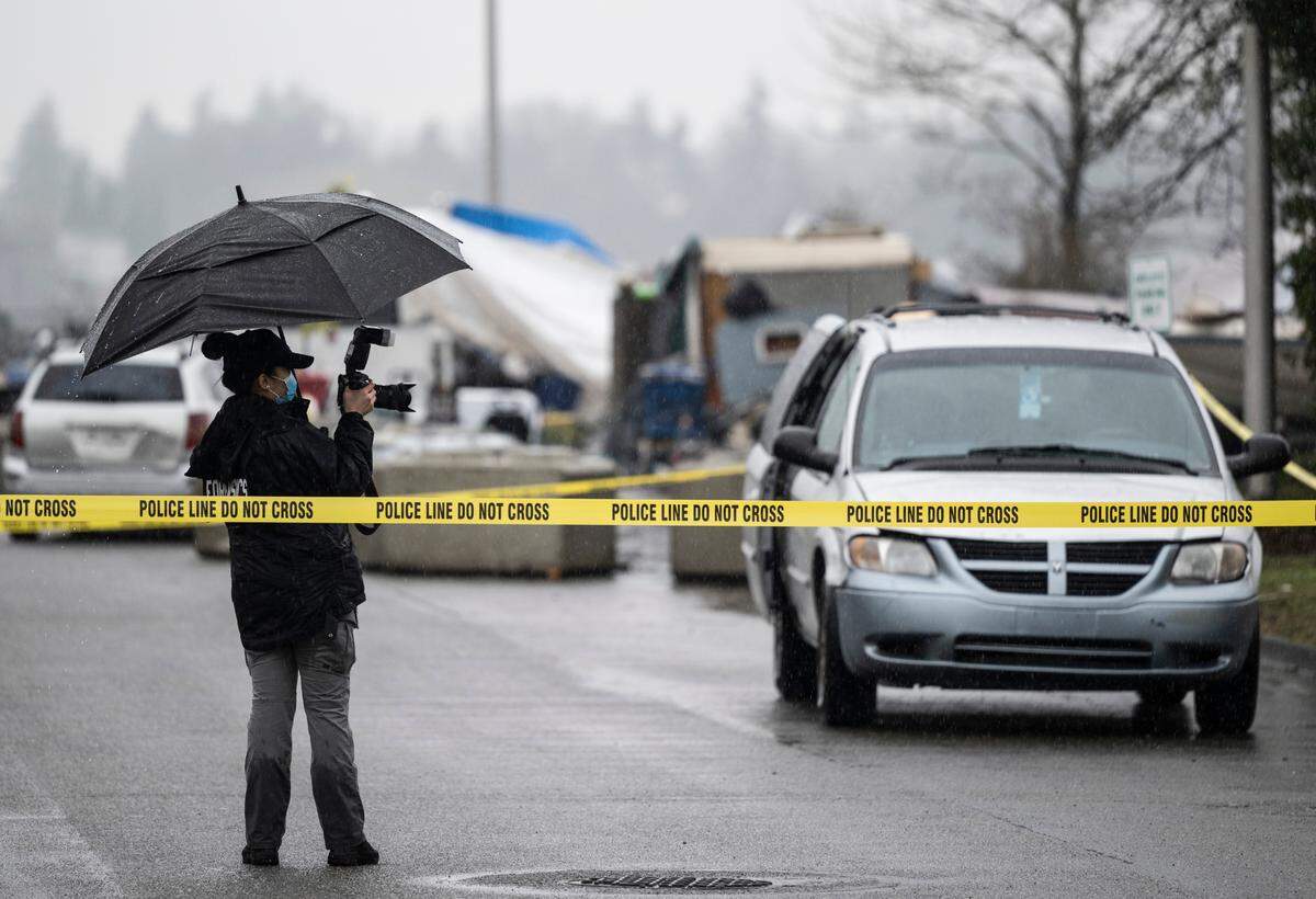 A crime scene technician takes photos of the vehicle where a woman was found shot and was pronounced deceased at the 4900 block of South Burlington Way in Tacoma, Wash. on Monday, Feb. 28, 2022.