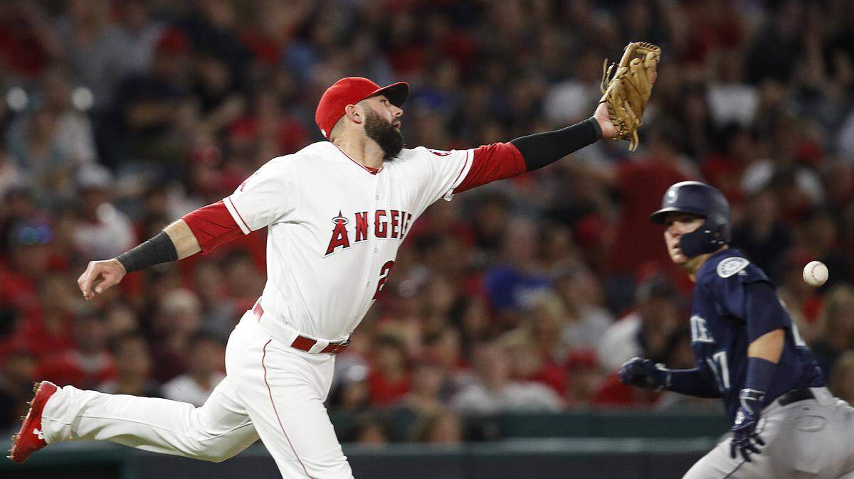 Los Angeles Angels’ Kaleb Cowart misses a ground ball hit by Seattle Mariners’ Kristopher Negron as Mariners’ Ryon Healy, background right, runs to third base during the sixth inning of a baseball game, Saturday, Sept. 15, 2018, in Anaheim, Calif. Healy scored on the play. (AP Photo/Jae C. Hong)