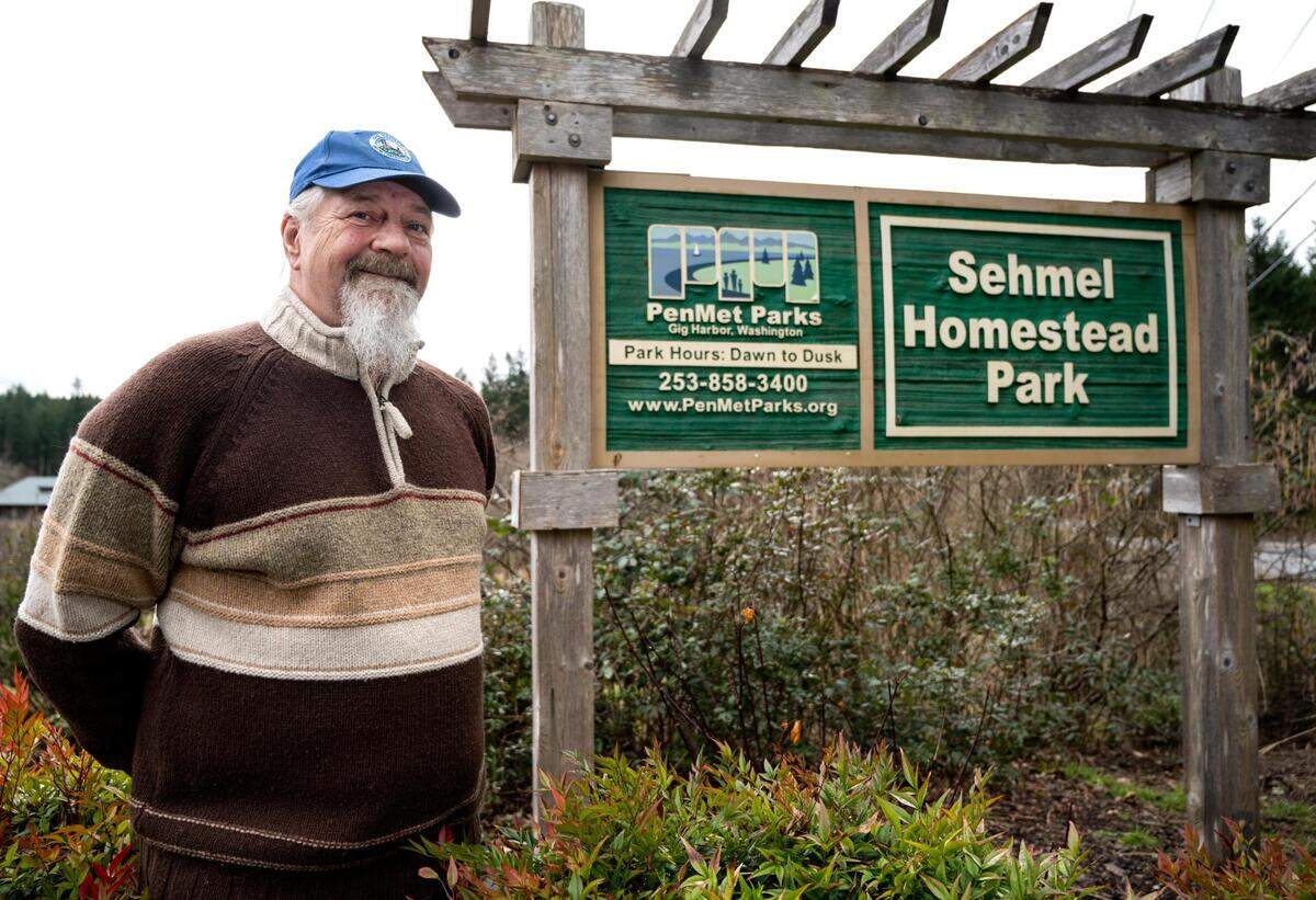 Bill Sehmel, a former parks commissioner and lifetime resident of Gig Harbor, poses for a portrait in front of the Sehmel Homestead Park sign at the park in Gig Harbor, Wash. on February 14, 2022. Sehmel served on the board for 11 years and is now campaigning for Gig Harbor to be annexed into the Peninsula Metropolitan Parks District.