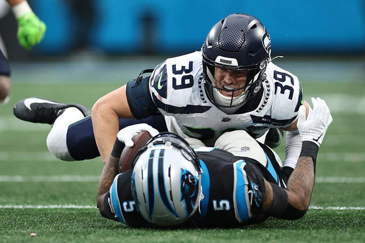 CHARLOTTE, NORTH CAROLINA - DECEMBER 28: Ty Okada #39 of the Seattle Seahawks tackles Rico Dowdle #5 of the Carolina Panthers during the third quarter at Bank of America Stadium on December 28, 2025 in Charlotte, North Carolina. (Photo by Jared C. Tilton/Getty Images)