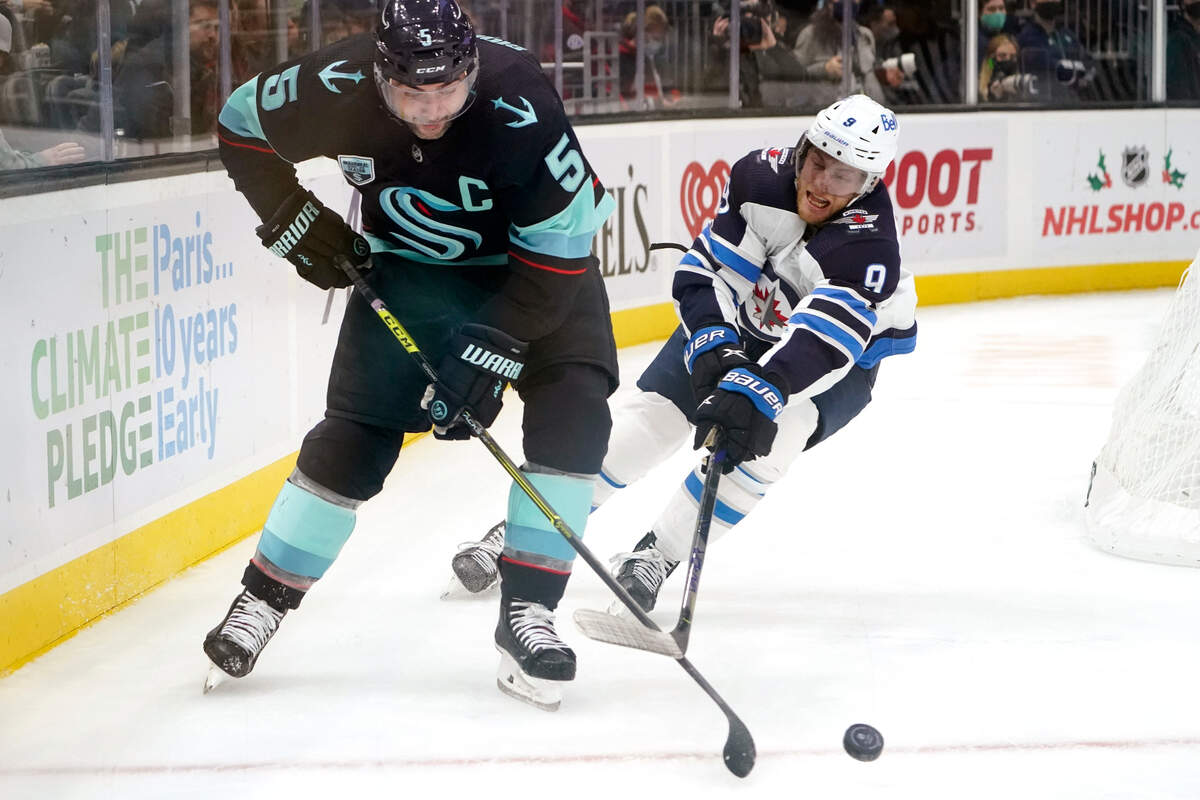 Seattle Kraken’s Mark Giordano (5) and Winnipeg Jets’ Andrew Copp (9) chase the puck in the second period of an NHL hockey game Thursday, Dec. 9, 2021, in Seattle. (AP Photo/Elaine Thompson)