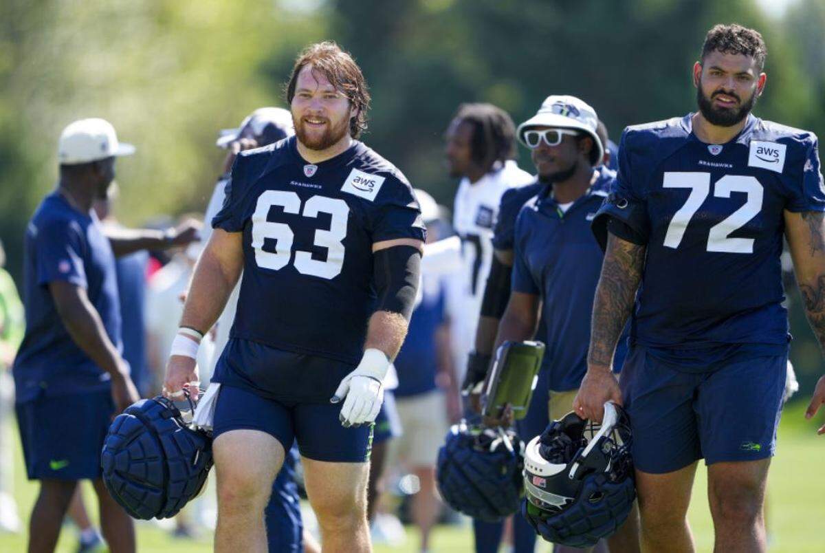 Seahawks center Evan Brown (63) walks off the practice field with right tackle Abe Lucas (72) during Seattle’s training camp in Renton on Aug. 3, 2023.
