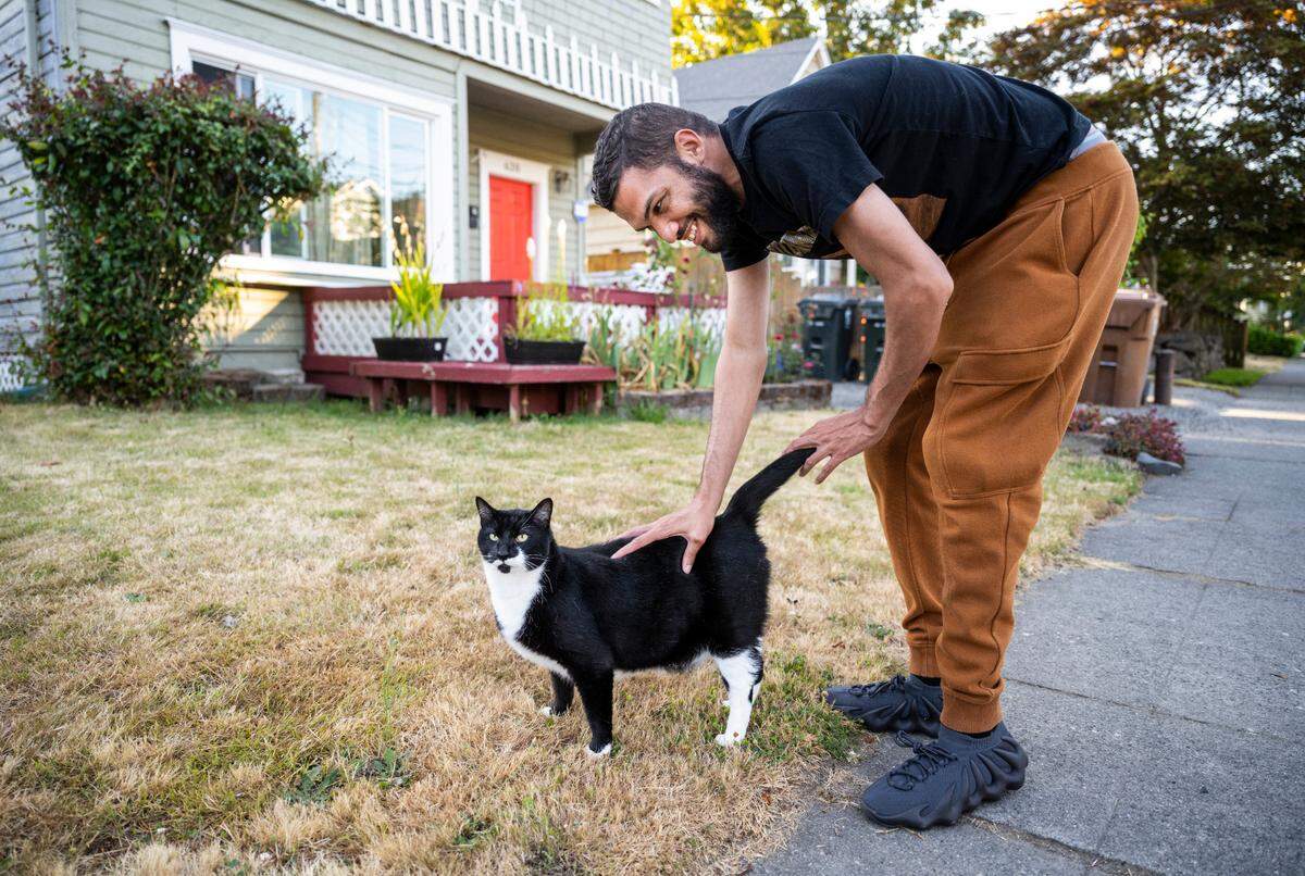 Chris Watson, Tiktoker and founder of the Catluminati, pets a cat while on a catwalk in Tacoma, Wash. on August 11, 2022.