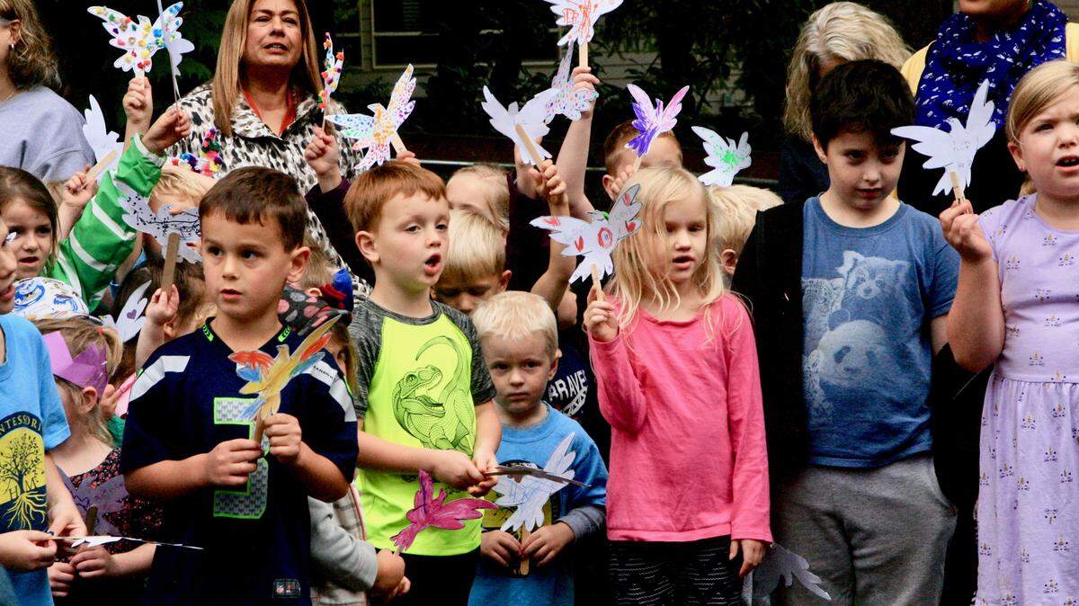 Holding their peace doves aloft while singing “Light a Candle for Peace” are Harbor Montessori students at the school’s annual Peace Pole celebration.
