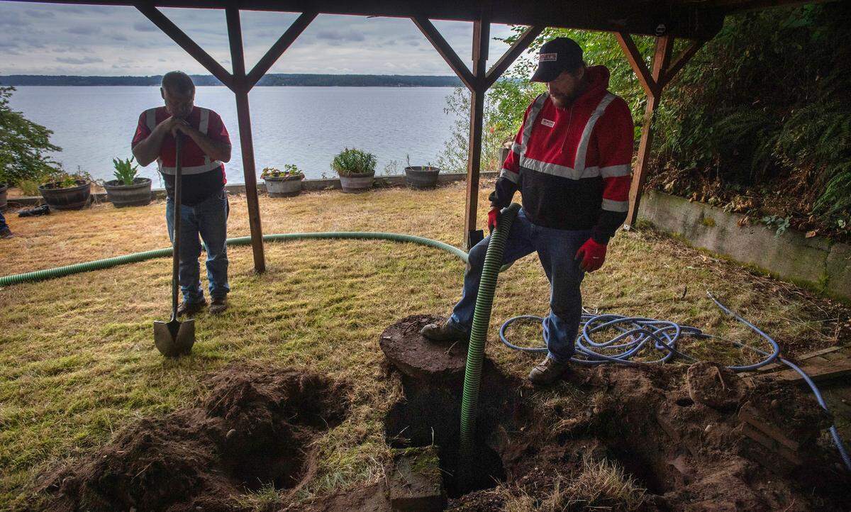 Hemley’s Septic Service owner Jerry Hemley (left) and maintenance specialist William Schmidt inspect and clean out a septic tank at a home on the Key Peninsula on Aug. 13.