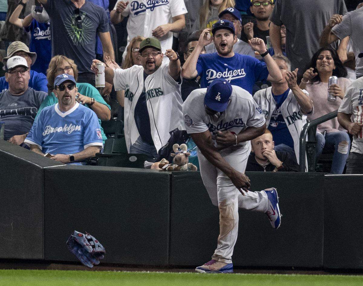 Los Angeles Dodgers right fielder Yasiel Puig throws his glove after he was unable to come up with a foul ball hit by Seattle Mariners’ Mitch Haniger into the first row of the seats, during the fifth inning of a baseball game, Saturday, Aug. 18, 2018, in Seattle. (AP Photo/Stephen Brashear)