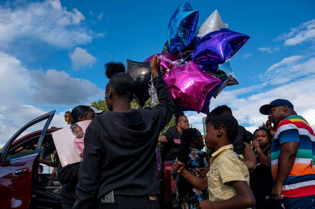 Friends of Iyana Ussery hold balloons and a picture of her as hundreds of people prepare for a peace walk in her memory on Thursday, July 7, 2022, in Tacoma.