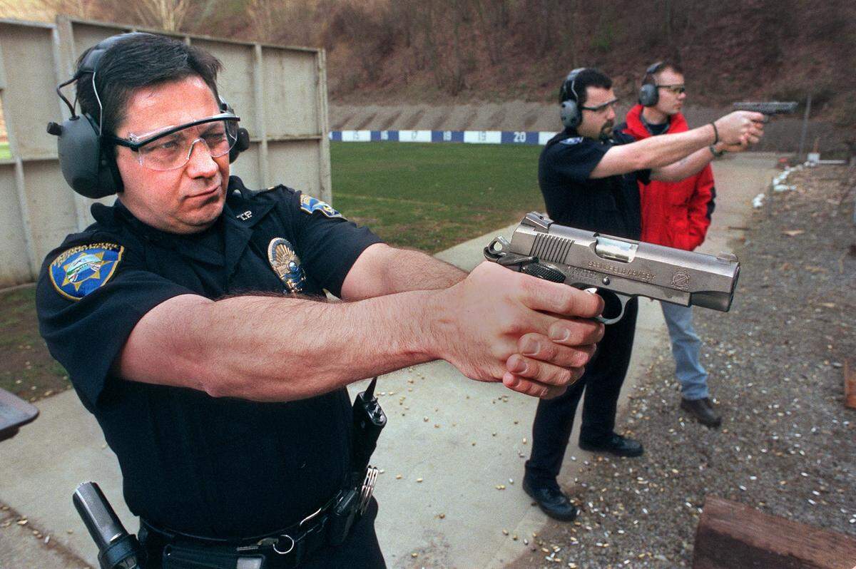 Tacoma Police Lt. Don Ramsdell takes aim with a Springfield Armory 1911 semi-automatic pistol at the Harrison Range, Tacoma Police’s firing range in March 2001. In the background is Tacoma Detective Jeff Turner shooting a Glock 21 pistol. Both pistols are 45 caliber guns. In the far background in red coat is Patrolman and Range Safety Officer Art Richwald supervising officers shooting all five guns they can select from. Lt. Ramsdell choose the Springfield 1911 for his new issue weapon. Tacoma is the first major police agency who will issue 1911 style pistol to their officers.